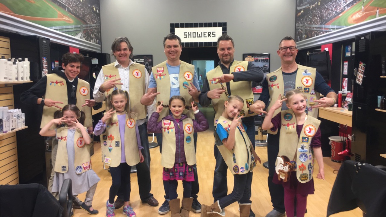 group of parents and children wearing vests displaying peace with hands