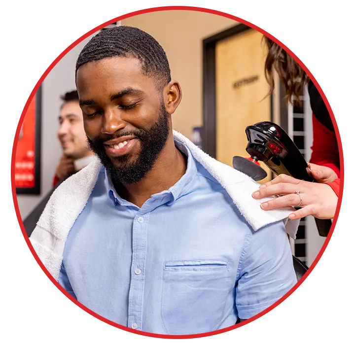 Sport Clips client receiving a neck and shoulder treatment with a massage tool